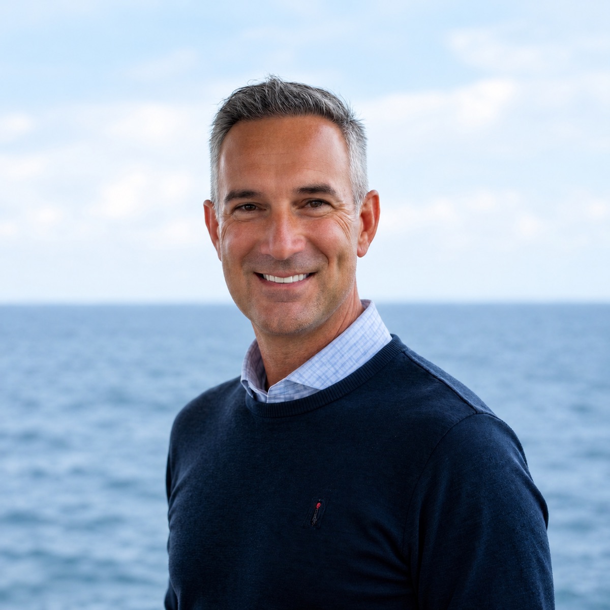 Headshot of Jonathan Hinton smiling in front of the ocean